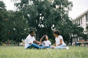 family sitting in grass under trees