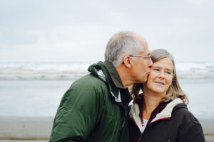 Elderly couple on the beach kiss on cheek