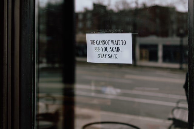 store front with closed sign on door due to covid-19