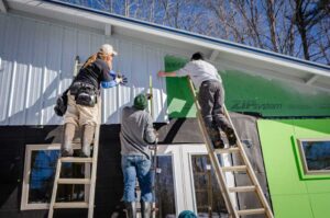 threee men installing siding on a house