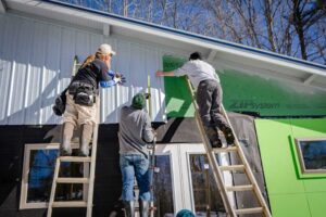 threee men installing siding on a house
