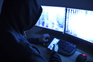 man wearing dark hood at computer
