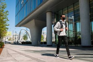 masked student walks alone on campus