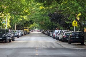 cars parked on both sides of long tree-lined city street